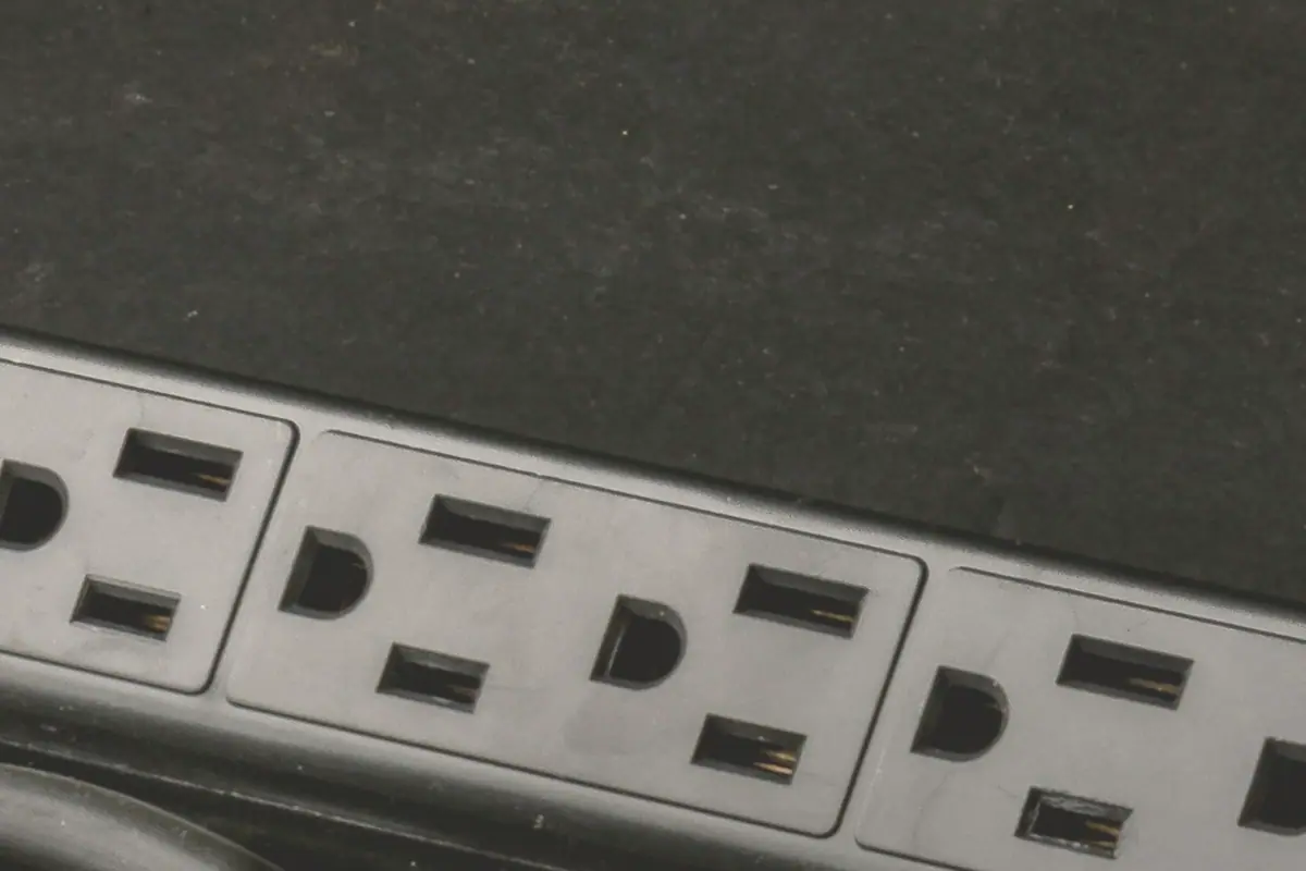 Clean close-up editorial photo of a power strip on a dark tabletop